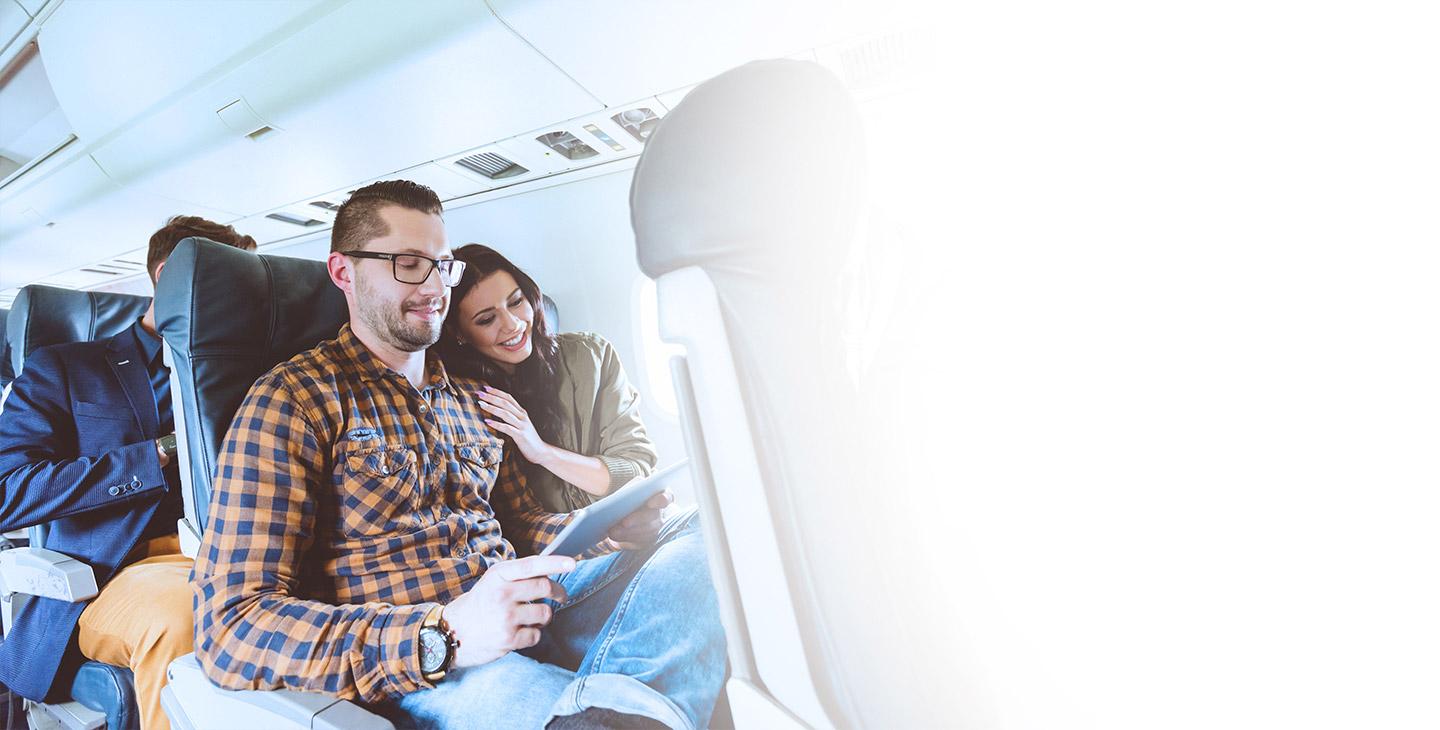 一男一女坐在一起享受飞机上的乘客体验, 看平板电脑
