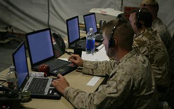 三名男性战士使用卫星通信通过他们的耳机进行通信, 在战术行动中心看笔记本电脑